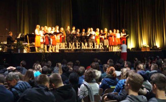 Chor auf Konzertbühne während eines öffentlichen Auftritts vor einem vollbesetzten Publikum, bei einem Chorsevent im Festsaal, beeindruckende Atmosphäre, Musik, Gemeinschaft, Advent-Verlag Events.
