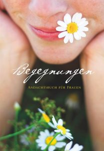Atemberaubliches close-up Bild eines Frauenlächelns mit einer Kamillenblume auf der Lippe, symbolisiert Einklang und Naturverbundenheit, passend für das spirituelle Advent-Verlag Buch "Begegnungen".