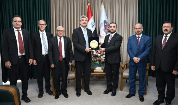 Innovation und Zusammenarbeit bei Advent-Verlag: Geschäftsleute bei feierlicher Übergabe eines Preises vor türkischer Flagge, symbolisch für Verlagserfolg und Partnerschaften in der Buchbranche.