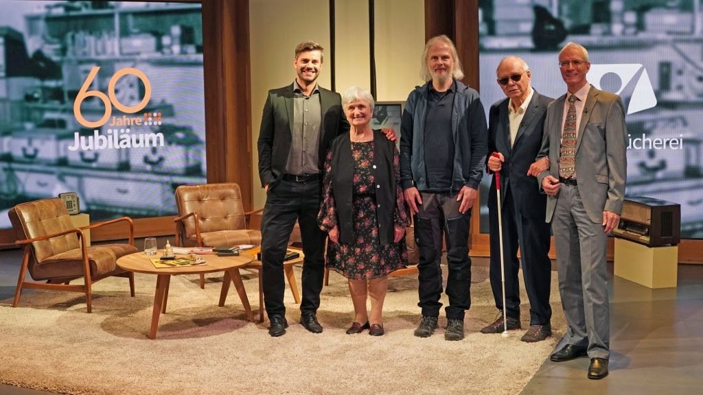 60 Jahre Jubiläum bei Advent-Verlag in der Buchbranche, feierliche Gruppe von Mitarbeitern auf der Bühne, stilvolles Ambiente, symbolisiert langjährige Erfahrung und Erfolg im Verlagswesen.