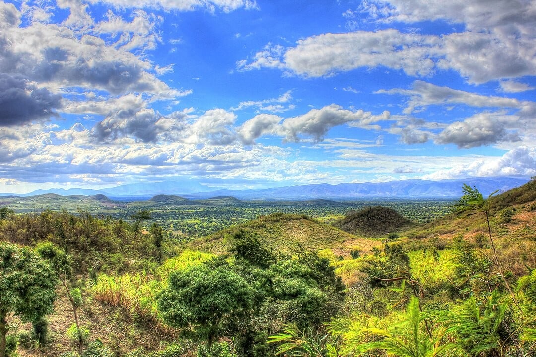 Himmel über grüner Hügellandschaft in Kenia mit Wolken und blauer Himmel, beworben von Advent-Verlag, ideal für christliche Inspiration und Naturliebhaber, Landwirtschaft und nachhaltiger Tourismus.