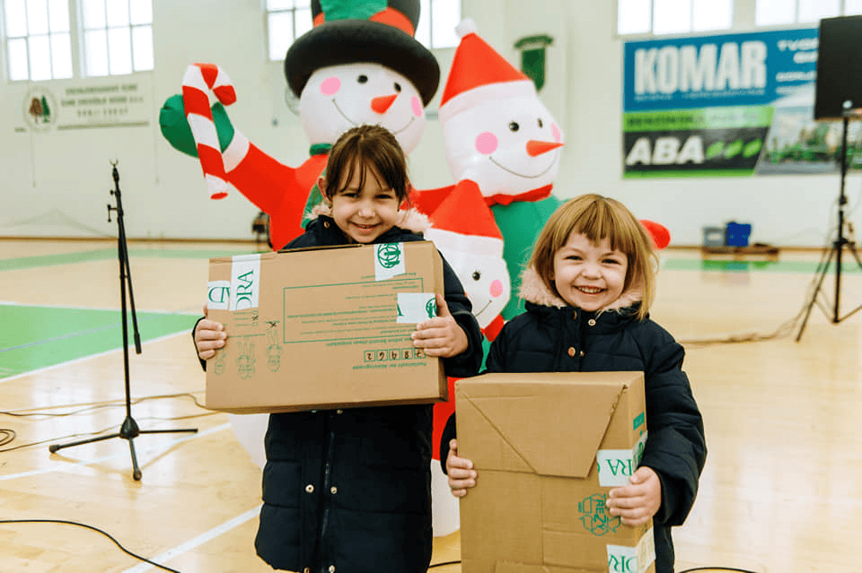 Weihnachtliche Kinderübergabe im Hallensport mit Advent-Verlag, festliche Stimmung, Kinder mit Paketen, Weihnachtsdeko, Schneemänner, Geschenkfeier, Weihnachtsveranstaltung Weihnachtsgeschenk.