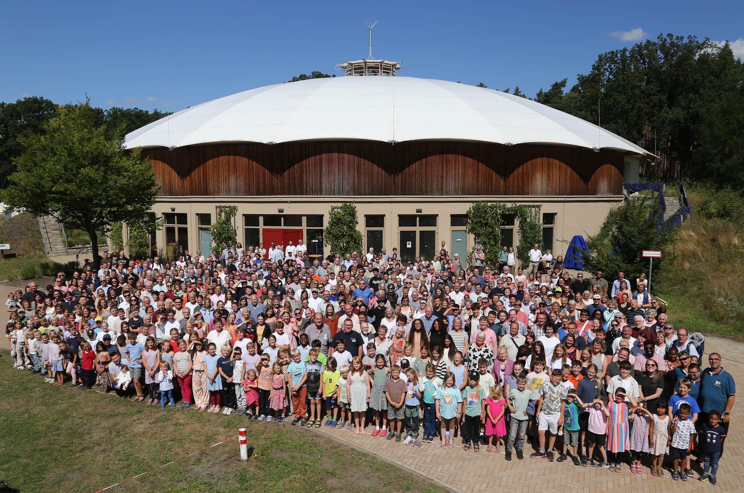 Große Gruppe von Menschen vor einem runden Veranstaltungsgebäude bei Hope Camp 2026 in Friedensau.