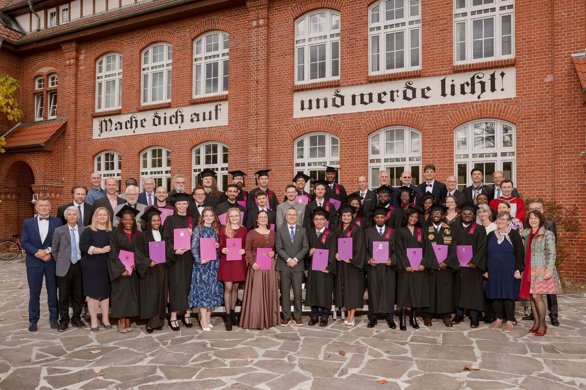 Absolventen der Theologischen Hochschule Friedensau bei ihrer Graduierung, viele in Roben und mit Urkunden.