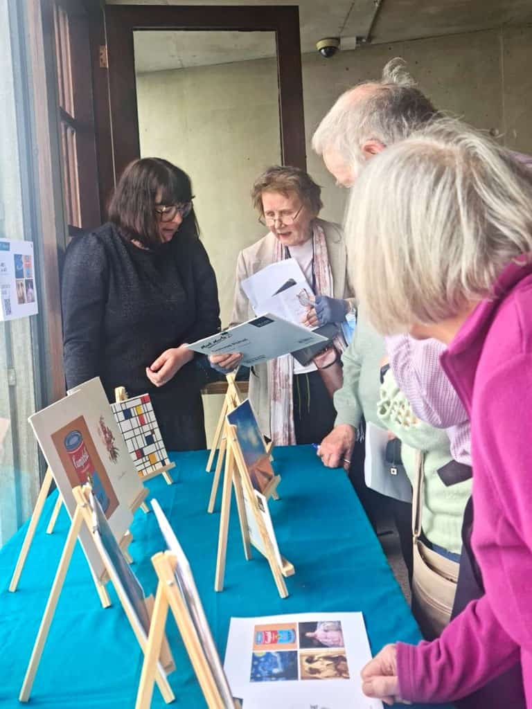 a group of people looking at a table with art on it