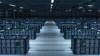 Data center with rows of server racks and blue-lit status LEDs across the cabinets in an expansive room.