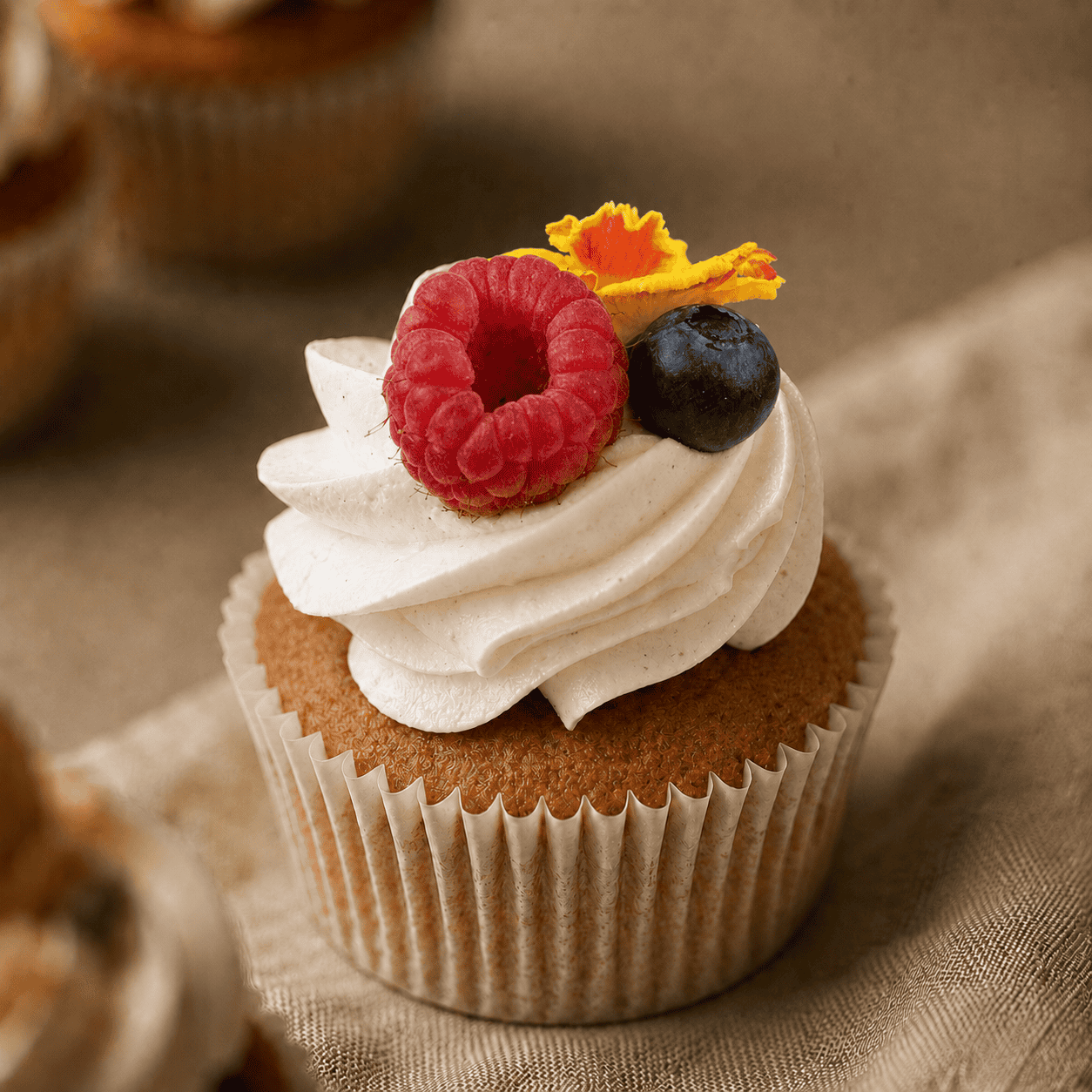 Bruiloft cupcake met bloem, framboos en blauwe bes