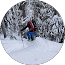 A hiker ascending a snowy mountain trail with stunning winter scenery in the background.