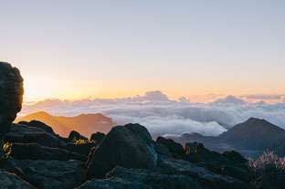 Cumbre montañosa al amanecer con nubes y cielo despejado en un paisaje natural.