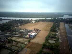 Cultivo agrícola y canales de riego en un paisaje rural junto a un río.