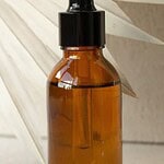 Flesje cosmetica in amberkleurig glas zonder etiket, voor een gedroogd palmblad