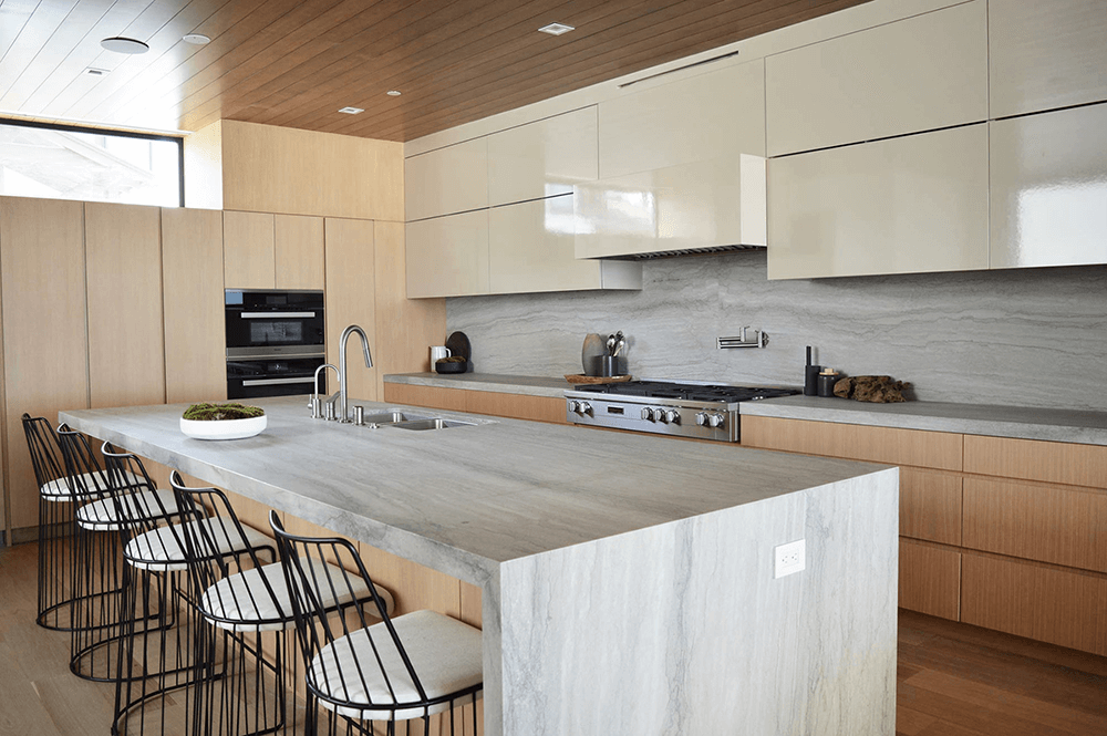 Elegant kitchen featuring White Pearl quartz countertops on a large island, complemented by black shaker cabinets and an undermount sink.