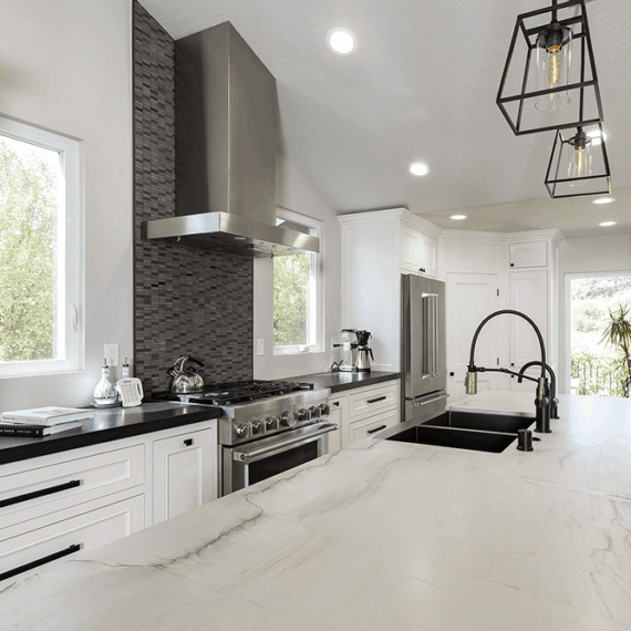Modern kitchen island with a polished Luce Di Luna quartzite countertop, featuring elegant veining and a black base with matching bar stools.