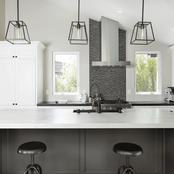 Modern kitchen island with a polished Luce Di Luna quartzite countertop, featuring elegant veining and a black base with matching bar stools.