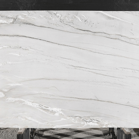 A close-up of a Luce Di Luna quartzite slab, showcasing its elegant natural stone veining and unique blend of cool grays and beige tones.