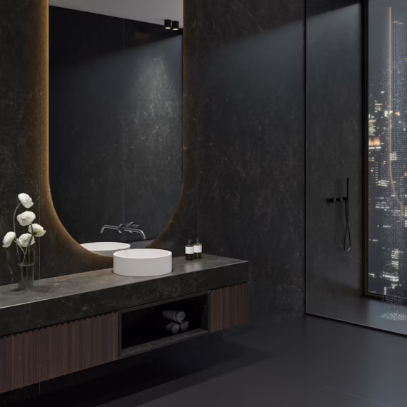 Moody penthouse bathroom remodel with a custom Phantome dark stone floating vanity and full wall cladding by Arlington Marble.