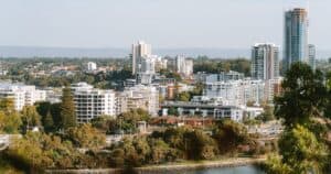 Πράσινα δέντρα και λευκά κτίρια του Περθ κάτω από ανοιχτόχρωμο ουρανό.