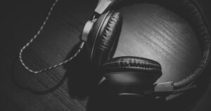 Μαύρα ακουστικά πάνω σε ξύλινη επιφάνεια σε ασπρόμαυρη λήψη.