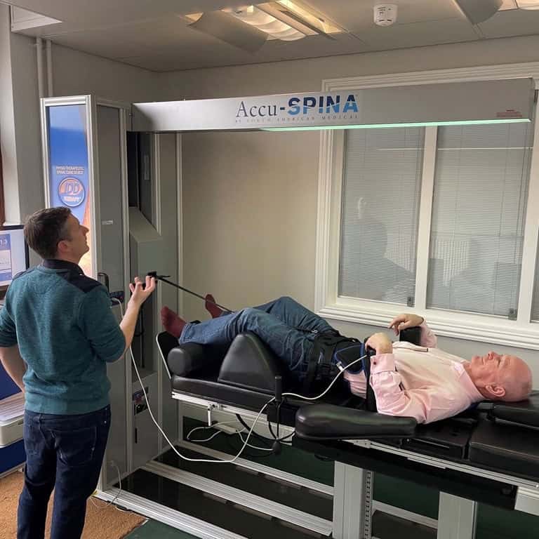 Male patient lying comfortably on Accu-SPINA IDD spinal decompression machine during therapy session to relieve back pain at Ashgrove Health Clinic, Wellingborough.