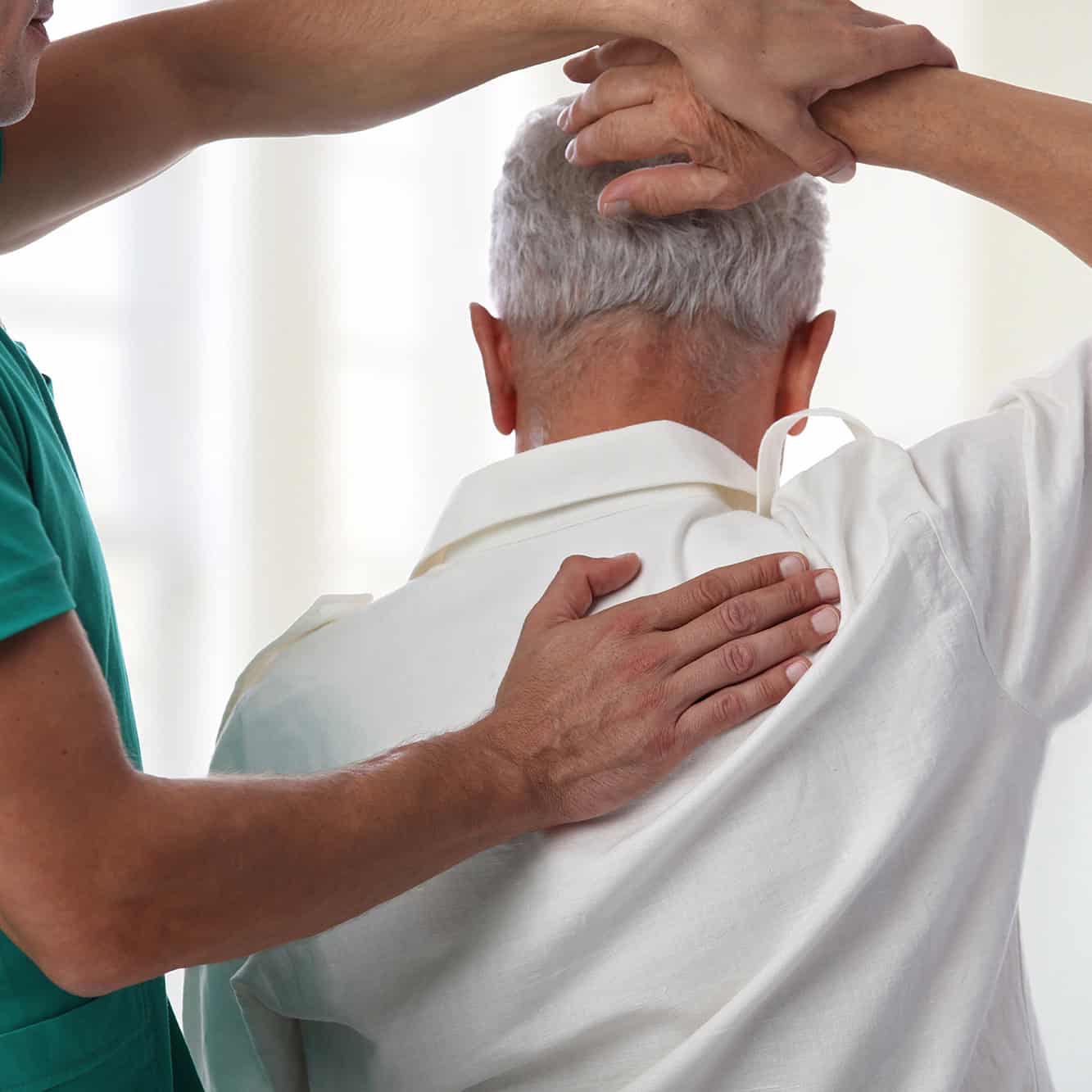 Physiotherapy or osteopathy for arthritic pain osteoarthritis assisting an elderly man with shoulder mobility exercises during a treatment session at Ashgrove Health Clinic in Rushden.