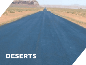 Freshly paved asphalt road stretching through desert terrain under clear sky.