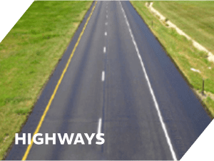 Freshly paved asphalt highway with clear lane markings and green roadside grass.