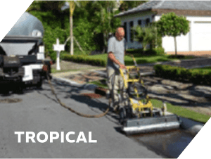 Asphalt repair worker using equipment on residential street.
