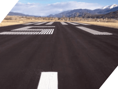 Newly paved asphalt runway with clear markings in a mountainous landscape.
