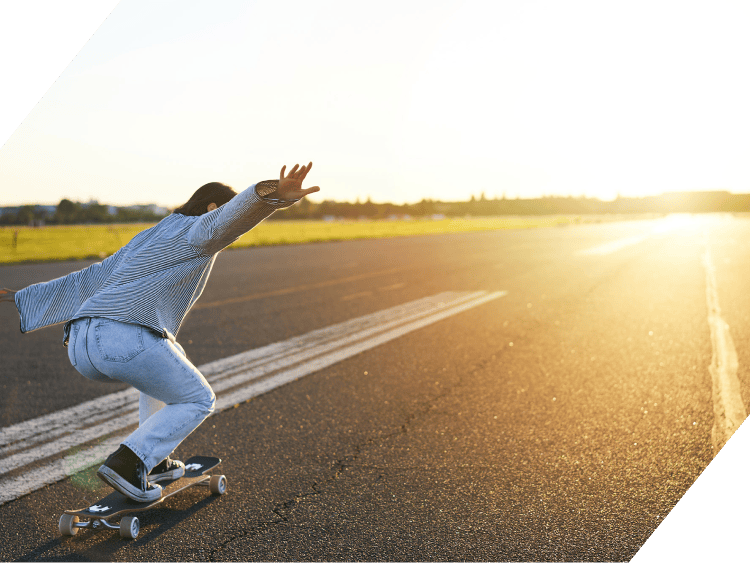 Skateboarder riding on an empty road at sunset for road safety.