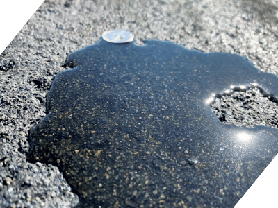 Close-up of asphalt with oil spill and gravel surface.