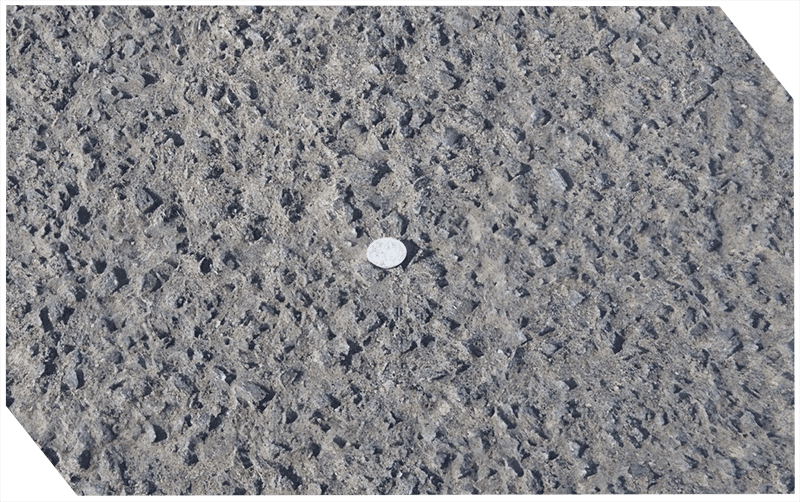 Close-up of asphalt surface with coin for scale.