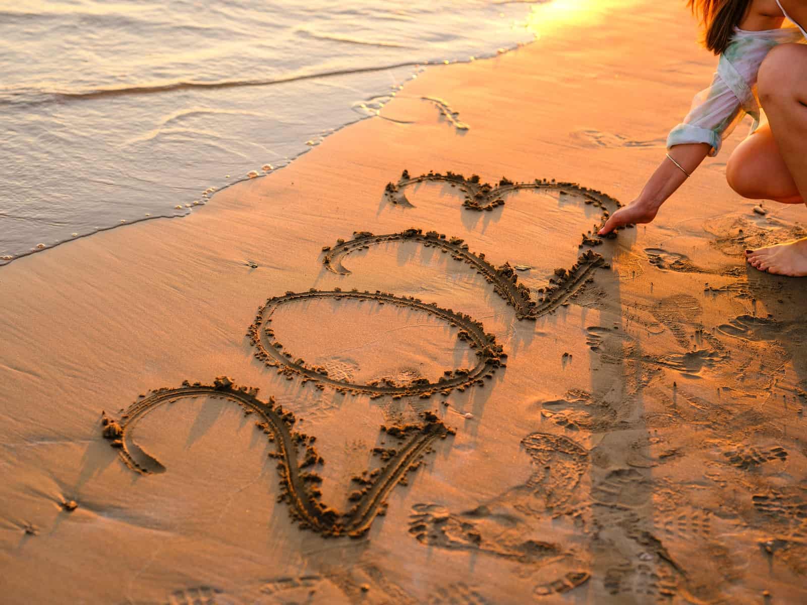 a person drawing a heart in the sand