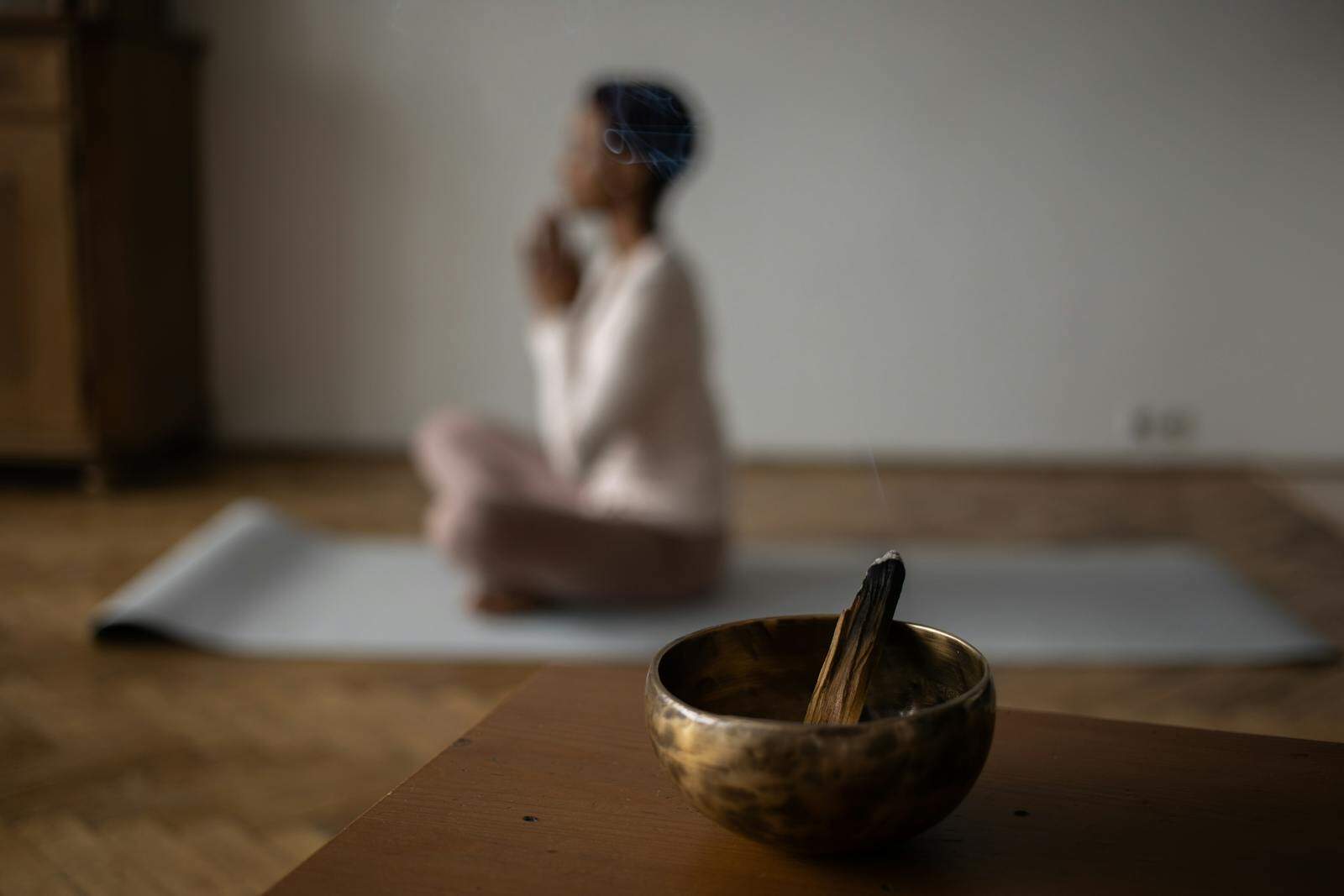 Mind-Body Practices, A serene indoor scene of meditation with an incense bowl and a woman practicing yoga.