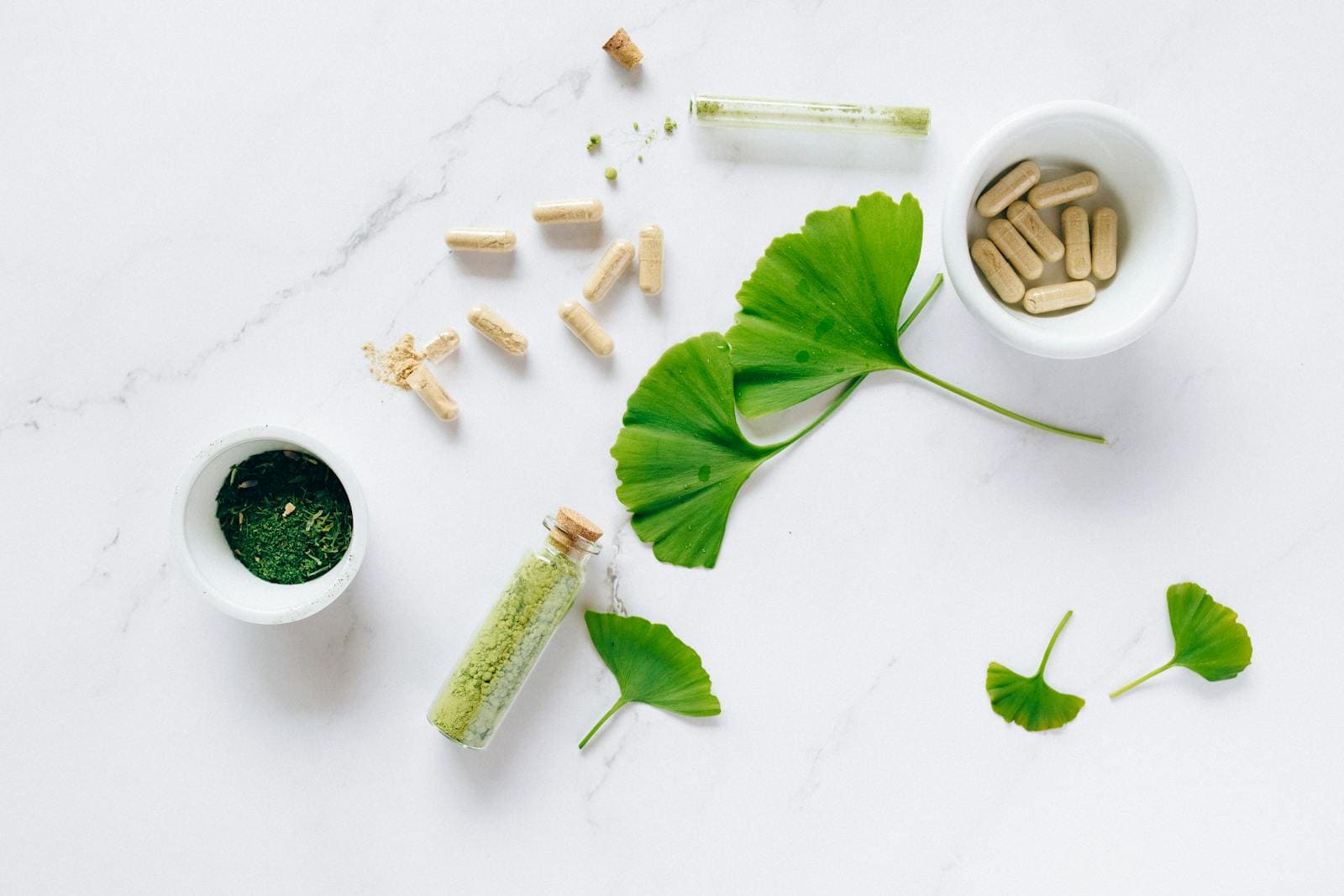 Naturopathy: Holistic Healing, Herbal remedies, Flat lay of herbal supplements with ginkgo leaves on marble surface, emphasizing natural health remedies.