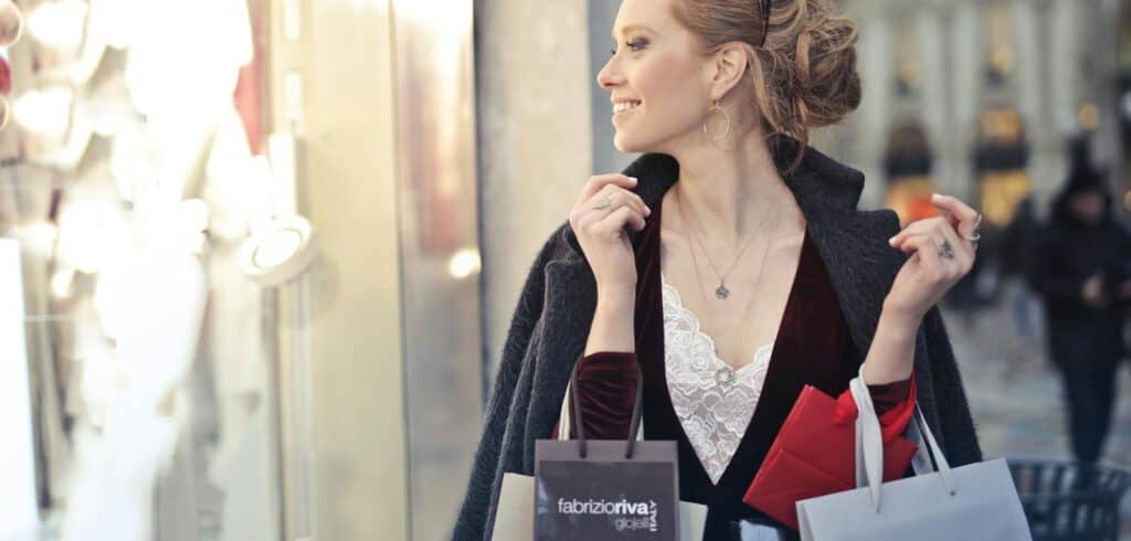 Smiling woman holding shopping bags in a city, enjoying a day of shopping. finances, zodiac, astrology, spending habits