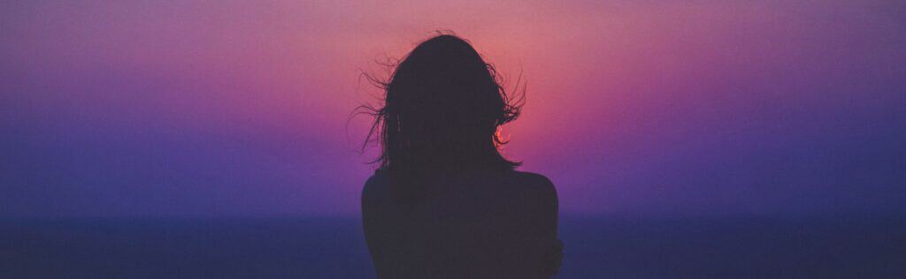 silhouette of a woman with pink and purple sky
