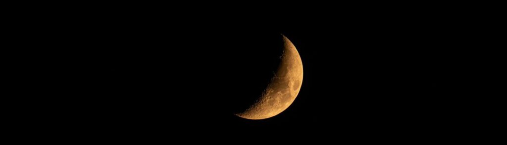 A vivid image of a crescent moon glowing against a clear night sky.