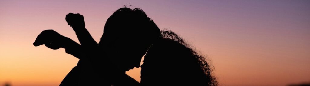 silhouette of man and woman kissing during sunset