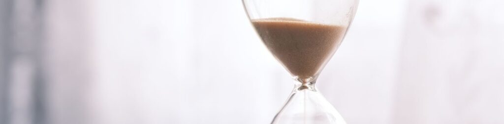 Minimalist hourglass filled with sand symbolizing time and patience, against a soft background.