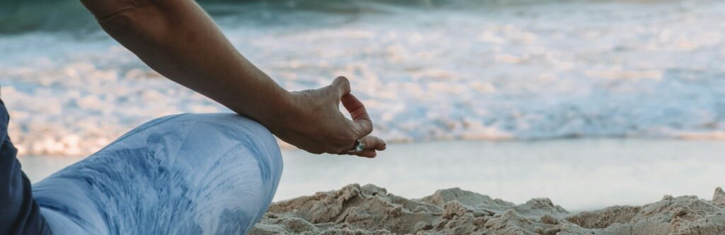 person in blue shorts sitting on beach shore during daytime