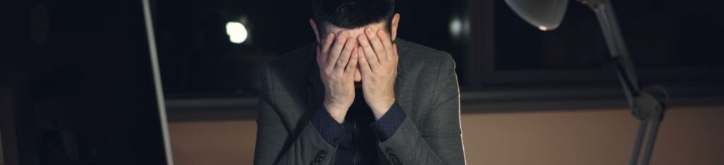 Businessman overwhelmed and stressed at his desk during late-night work hours.