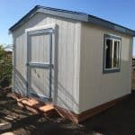 Small white garden shed with blue trim and window, ideal for storage or outdoor use.