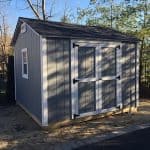 Garden shed with gray siding and black roof, ideal for outdoor storage solutions.