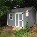 Garden shed with gray exterior, white double doors, and a small window for natural light.
