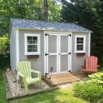 Garden shed with double doors and windows, surrounded by greenery and outdoor seating. Perfect for g.