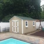 Garden shed with a play area and swings in backyard.