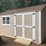Garden shed with beige siding, white trim, and double doors, ideal for outdoor storage solutions.