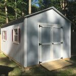 Garden shed with double doors, windows, and a wooden ramp for easy access. Perfect for outdoor stora.