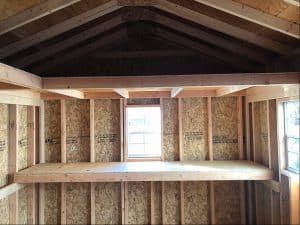 Unfinished wooden shed interior with framing and exposed insulation, ready for finishing.