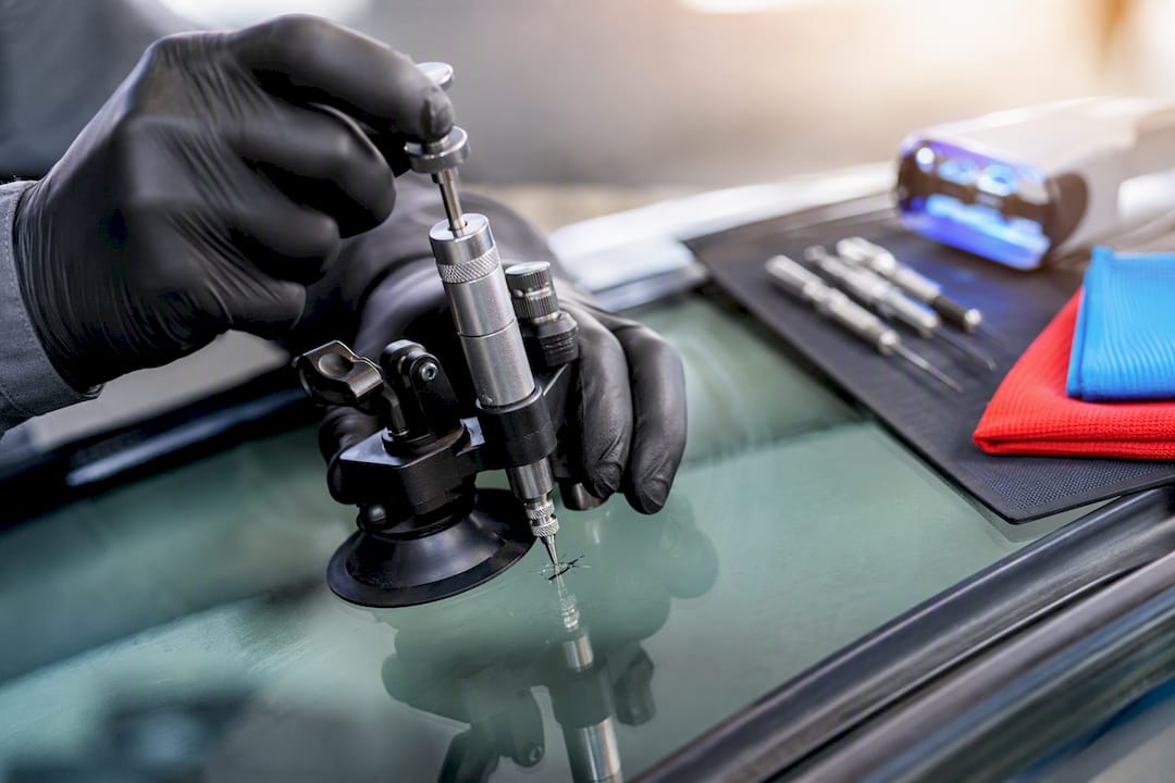 Technician injecting resin into windshield chip